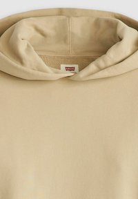 Sudadera beige de tejido suave y texturizado. Cuenta con una gran capucha acogedora y una pequeña etiqueta roja de Levi's cerca del cuello.