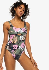 Maillot de bain une pièce avec un motif floral en rose, blanc et vert sur fond noir, avec un décolleté carré et un détail découpé.