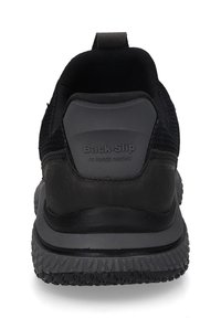 Schwarze Slipper aus strukturiertem Mesh-Obermaterial mit glattem Gummiferse. Die Sohle hat ein Profilmuster für Grip und ist mit "Back-Slip" beschriftet.