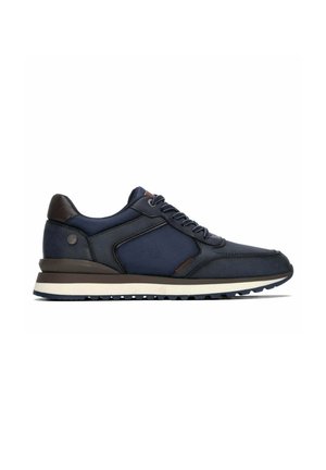 Zapatilla baja azul marino y negra con cordones delanteros, suela acolchada y paneles laterales texturizados, mostrada de perfil sobre un fondo blanco.