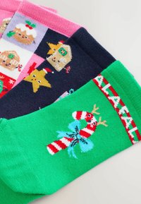 Farverige julestrømper med mønstre af slikstokke, pepperkagehuse og stjerner. Materialerne ser bløde og strikkede ud med forskellige teksturer.