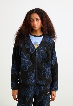 Zwarte fleecejacket met blauw bloemenpatroon, ritsluiting en geribbelde manchetten. Gecombineerd met een lichtblauw T-shirt met een grafische rozenontwerp.