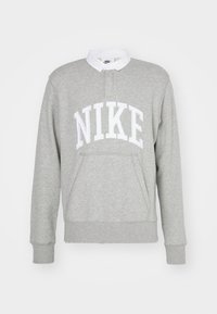 Siva trenirka s belim logotipom "NIKE", rebrastimi manžetami in ovratnikom. Narejena iz mehke tkanine z žepom spredaj.