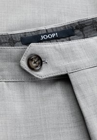 Gray fabric close-up featuring a button and the label "JOOP!" with a tonal pattern in the interior lining.