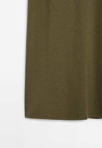 Tissu en maille côtelée verte présentant une texture lisse, coupé droit au niveau de l'ourlet, sans motifs ni ornements visibles.