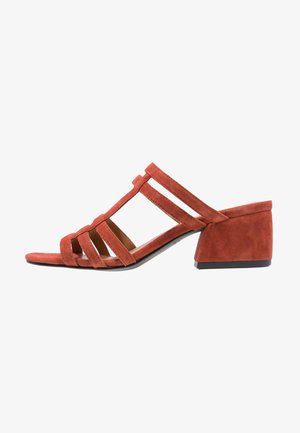 Sandalia de ante rojo con punta abierta, múltiples tiras y tacón bajo en bloque, mostrada de perfil sobre un fondo blanco.