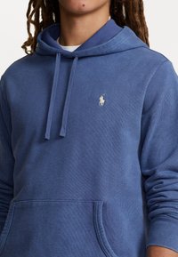 Felpa con cappuccio blu navy realizzata in tessuto morbido, con tasca a marsupio, cappuccio con coulisse regolabile e piccolo logo ricamato sul petto.