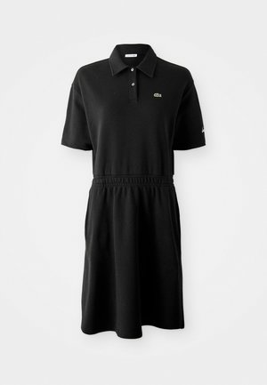 Robe polo noire à manches courtes avec col, deux boutons, ceinture élastique et petit logo croco vert sur la poitrine.