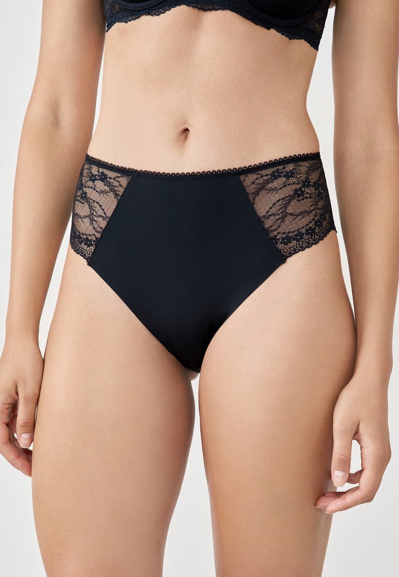 Czarne majtki z wysokim stanem, z przezroczystymi koronkowymi wstawkami po bokach, wykonaną z miękkiego materiału i delikatnym falbankowym wykończeniem wzdłuż pasa.