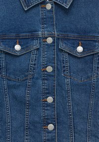 Veste en denim à boutons-pression argentés, avec deux poches poitrine et des coutures contrastées. Tissu bleu foncé avec une texture rugueuse.