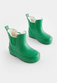 Botas de tobillo verdes de goma con forro de piel sintética, paneles elásticos y suela texturizada para un mejor agarre. Incluyen tiradores para facilitar su uso.