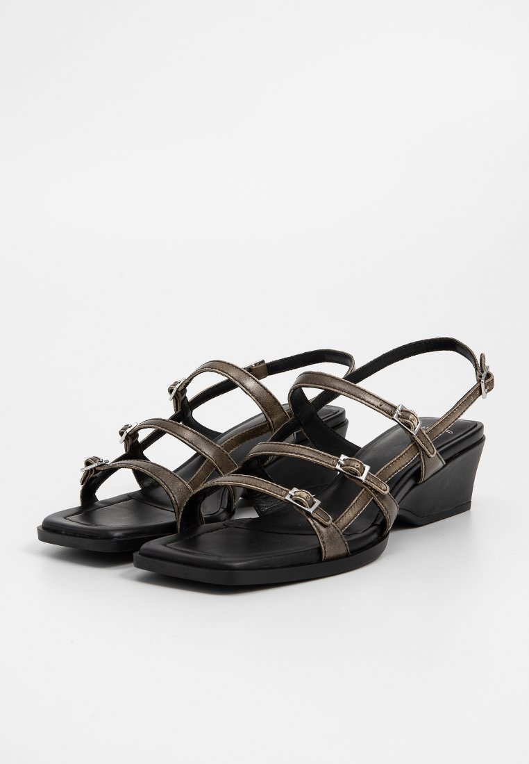 Sandales à brides avec une finition métallique brune, dotées d'un talon compensé et d'une semelle noire rembourrée. Boucles réglables sur les brides.