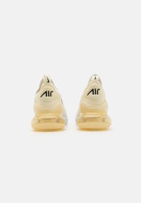 Vita sportskor i vitt med gula genomskinliga mellansulor och svart "AIR"-logotyp på hälen. Mesh-övre med texturerade accenter.