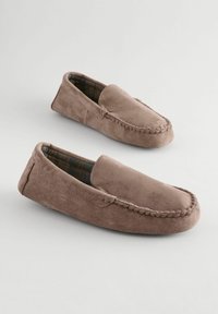 Brune ruskind slapsssere med en syet tå, slip-on design og en ternet foring. Blød tekstur, afrundet form og ingen synlig hardware.