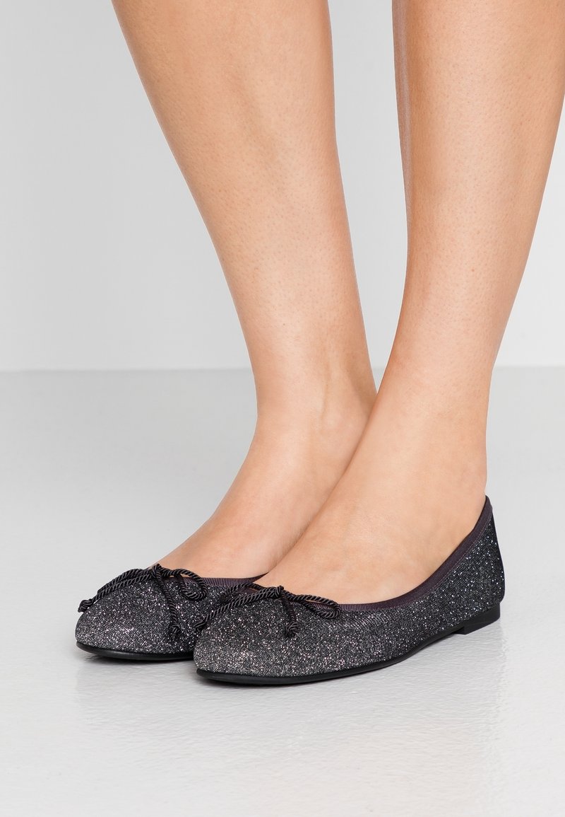 Ballerines noires avec paillettes, bout rond et accent en nœud en tissu. Texture lisse et profil de talon bas.