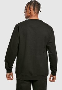 Felpa nera con scollo rotondo e maniche lunghe. Realizzata in materiale morbido, presenta una vestibilità comoda e polsini e orlo a costine.