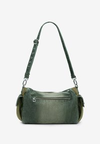 Sac en tissu vert avec sangle réglable, poche avant zippée et accents texturés sur les côtés. Présente une finition douce et délavée.