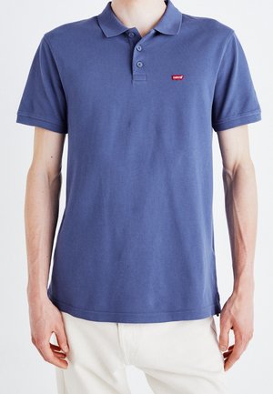 Blue polo shirt with a collared neckline, three-button placket, and Levi's logo. Made from cotton, featuring short sleeves and a relaxed fit.