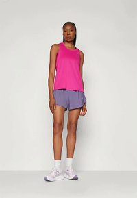 Fuksiaroosa sportsi tank top kerge lõikega, kombineeritud lavendli lühikestega. Modell kannab heledat purpurse värvi jooksujalatseid ja valgeid sokke.