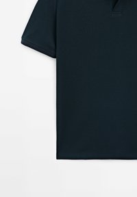 Polo bleu marine foncé à manches courtes, en tissu texturé, avec un ourlet droit, sans boutons visibles ni logos.