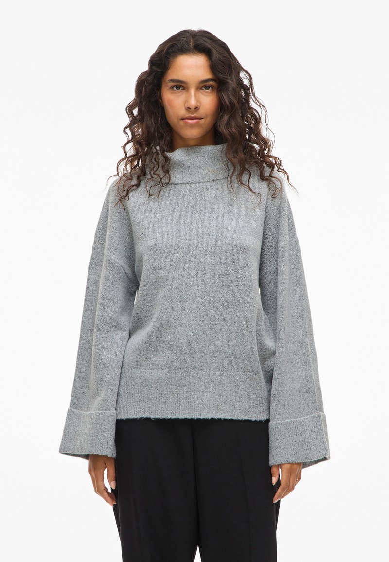 Helles graues, übergroßes Sweatshirt mit hohem Kragen, weiten Ärmeln und rohem Saum, aus einem weichen Strickmaterial hergestellt.