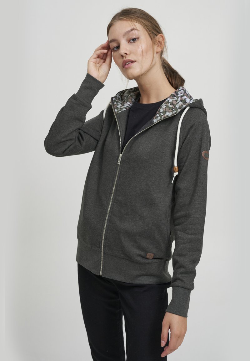 Felpa grigia con zip, con fodera del cappuccio a motivo floreale, coulisse con dettagli in legno e una toppa con il logo sul maniche sinistra.