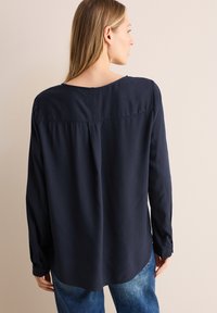 Navyblauwe blouse met lange mouwen van een textuurstof, met een ronde hals en een ontspannen pasvorm. Beschikt over knoopmanchetten en een gebogen zoom.