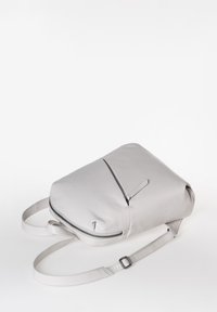 Zaino in pelle grigia con una texture liscia, dotato di una tasca frontale con zip e spallacci regolabili. Design minimalista, forma morbida e arrotondata.
