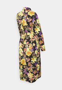 Robe floral em tecido preto, apresentando vibrantes flores amarelas, roxas e verdes. Mangas longas, colarinho e um detalhe de cintura amarrada.