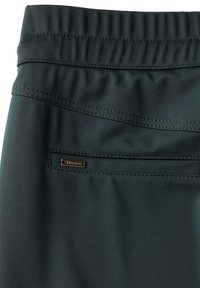Mörkgröna träningsbyxor med en texturerad midja, elastiska veck och en liten ficka med dragkedja som har en metallisk logotyp.