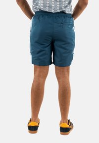 Shorts de baño azules con una cinturilla elástica y un bolsillo trasero. Fabricados con un material ligero, poseen una textura suave y detalles laterales.
