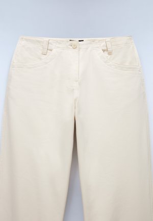 Beige katoenen broek met een gladde textuur, voorzien van zijzakken, een knoopsluiting en riemlussen. Geen zichtbare patronen of accenten.