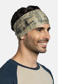 Banda para la cabeza de algodón con un patrón camuflado en beige y gris, que presenta una textura suave y un diseño ancho. Se ajusta cómodamente a la cabeza.