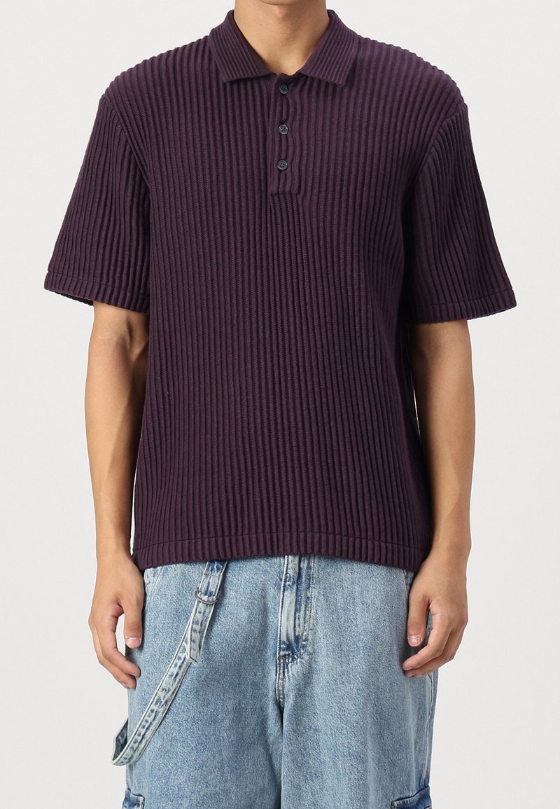 Fialové žebrované polo tričko s tříknoflíkovou légou a krátkými rukávy, v kombinaci se světle modrými džínovými cargo šortkami.