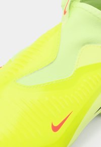 Adidași sport galbeni strălucitori cu swoosh roșu Nike, suprafață texturată și design slip-on, prezentați dintr-o vedere apropiată.