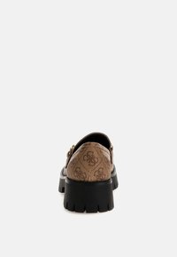 Scarpa slip-on con motivo marrone, suola nera chunky e dettagli in hardware dorato, caratterizzata da una tomaia in tessuto testurizzato e un design arrotondato.
