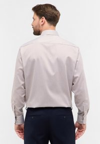 Lange mouwen shirt in lichtbeige met smalle verticale strepen in donkere tinten. Voorzien van een klassieke kraag en knoopmanchetten.