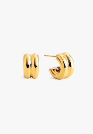 Naušnice u zlatnoj boji s glatkom, poliranom površinom. Jedan dizajn sadrži zaobljene oblike; drugi je debela, zakrivljena šuplja naušnica s utorima.