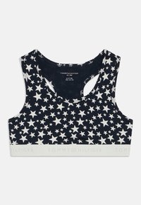 Marine sportsbh med hvitt stjernemønster, rund hals, åpen rygg og elastisk band med "TOMMY HILFIGER"-tekst i hvitt.