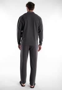 Chándal gris de manga larga con cuello con cremallera y ribetes en contraste; pantalones holgados que llegan hasta los tobillos; textura de tela suave.