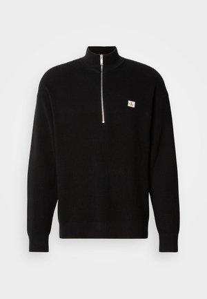 Čierny pletený sveter s vysokým golierom a zapínaním na zips. Má malú logo nášivku na ľavej strane hrude. Rebrovaná textúra a dlhé rukávy.