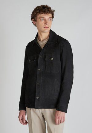 Zwarte suede jas met een knoopsluiting aan de voorkant, twee borstzakken en een kraag. Beschikt over een gladde textuur en een getailleerde pasvorm.