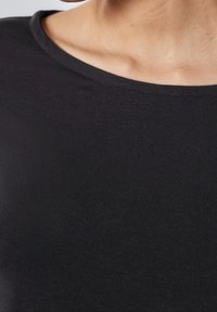 Svart kortärmad skjorta gjord av ett slätt, stretchigt tyg med rundad halsringning och en kroppsnära design.