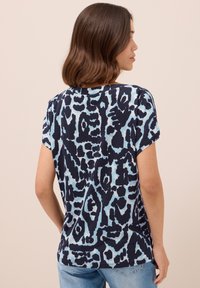 Kortärmad blå och marin t-shirt med ett geometriskt leopardmönster, med rund halsringning och avslappnad passform.