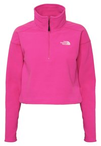Polarowy pulower w jaskrawym różowym kolorze z wysokim kołnierzem, zamkiem błyskawicznym do połowy z przodu oraz białym logo na górnej lewej stronie. Gładka tekstura.