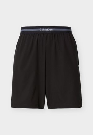 Schwarze Calvin Klein Herren-Shorts mit elastischem Bund und gebrandetem Streifen, knielang, schlichtes Design, flach auf weißem Hintergrund präsentiert.