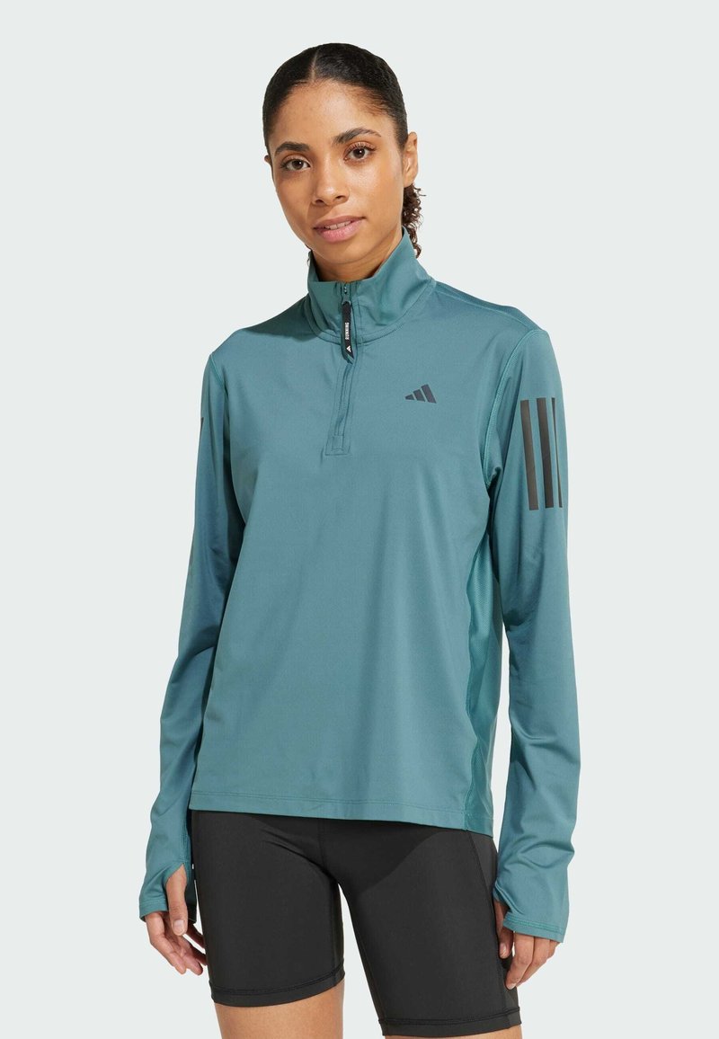Teal long-sleeve sports shirt with half-zip collar. Features black three-stripe design on sleeves and moisture-wicking fabric.