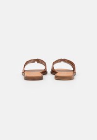 Brune læder sandaler med flad sål, åben bag og minimale stropdetaljer. Såle har en lys orange farve med brandnavn.