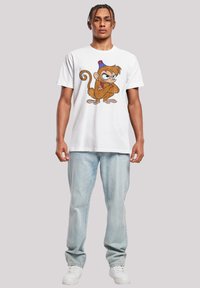 Hvit bomull t-skjorte med et grafisk trykk av en tegneseriekokk med blå hatt. Båret med lyseblå jeans og hvite sneakers.