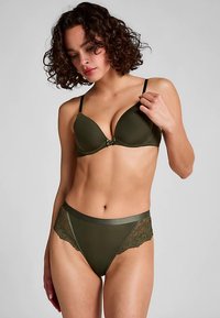 Olijfgroene beha met gladde cups en verstelbare bandjes, voorzien van een decoratieve metalen sluiting in het midden. Bijpassende high-waisted slip met kanten accenten.